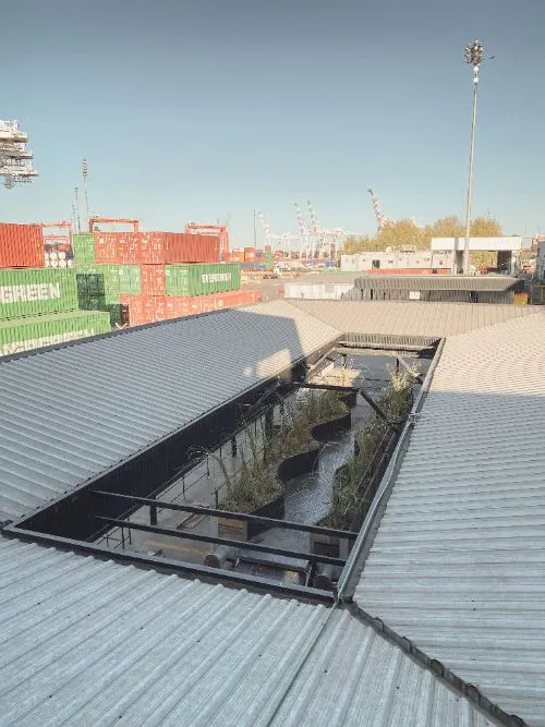 Vista aérea del vagón recién plantado entre los techos de la terminal, con los contenedores del puerto detrás