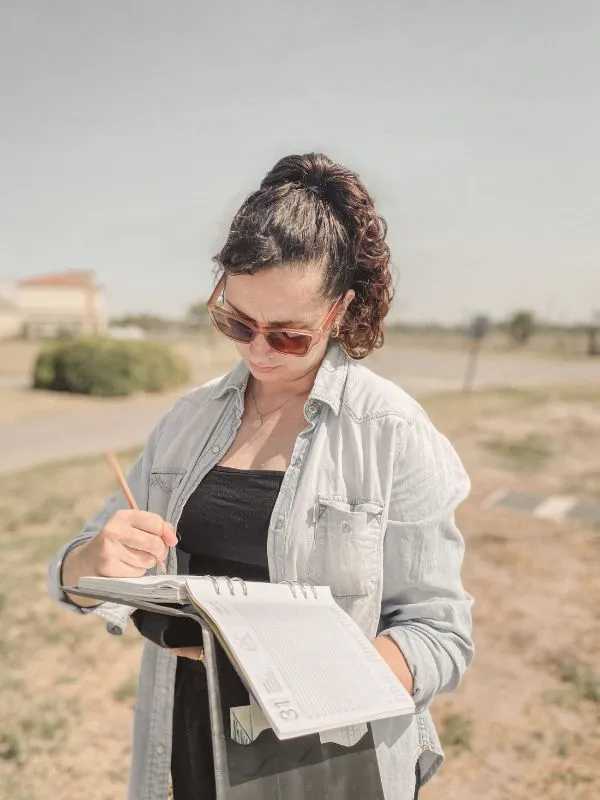 Lu relevando un terreno, tomando notas en su cuaderno de obra